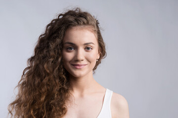 Portrait of a gorgeous teenage girl with curly hair. Studio shot, white background with copy space