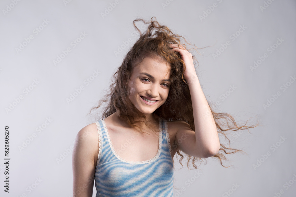 Wall mural Portrait of a gorgeous teenage girl with curly hair. Studio shot, white background with copy space