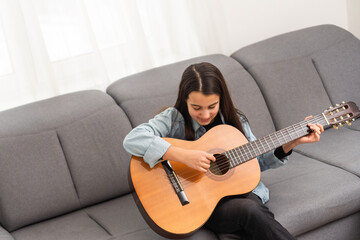 beautiful young girl plays guitar at home