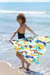 Smiling woman with colorful cloth standing on beach