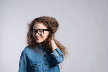 Portrait of a gorgeous teenage girl with curly hair and eyeglasses. Studio shot, white background...