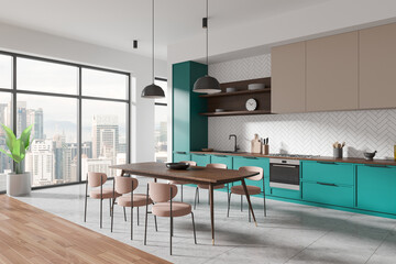 Modern kitchen interior with teal cabinets and wooden table, light-filled space with large windows...