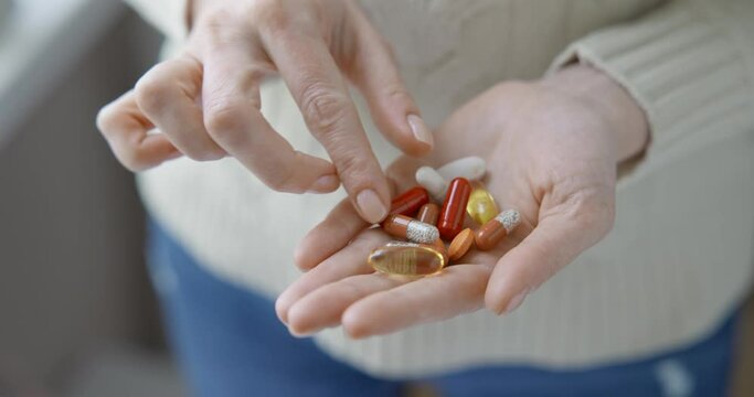 pharmacy and treatment concept - close up view of Caucasian woman holding capsules and tablets in her hand