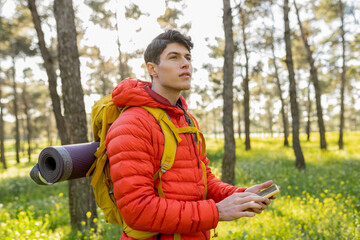 Young Man Hiking in Forest with Backpack and Smartphone
