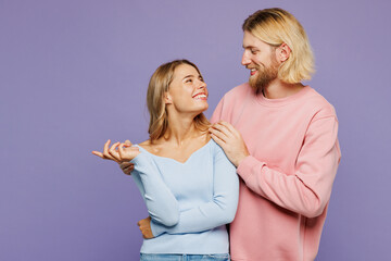 Young smiling happy couple two friends family man woman wear pink blue casual clothes together hug cuddle embrace look to each other isolated on pastel plain light purple background studio portrait.