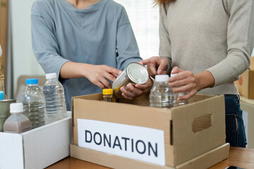 charity, donation and volunteering concept. Volunteer prepare foodstuff box containing food to...