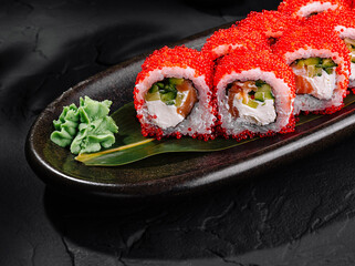 Delicious red caviar sushi roll on elegant dark plate