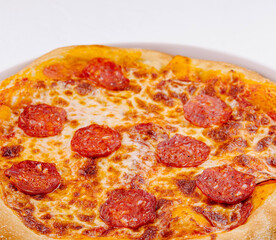 Freshly baked pepperoni pizza on white plate