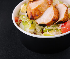 Delivery bowl with Caesar salad isolated on black