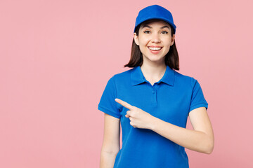 Professional fun delivery girl employee woman wear blue cap t-shirt uniform workwear work as dealer courier point index finger aside on area isolated on plain pink background studio. Service concept.