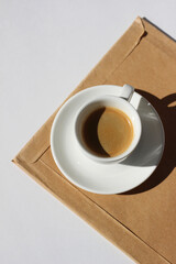 Freshly Brewed Espresso on Parcel with  Documents on White Office Desk Background.