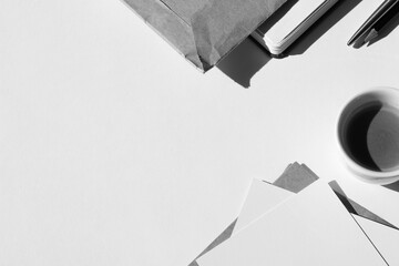 Monochrome Business Flatlay. Blank Paper Cards, Kraft Envelopes, Pencil, Notebook, Coffee Cup on Workplace Desk. 