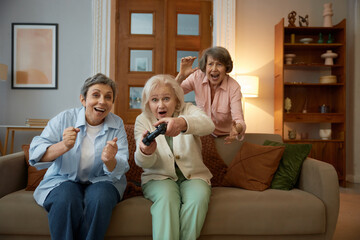 Overjoyed excited aged women friends playing video games together