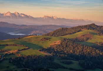 Mountain scenery with green pastures and rocky mountains in the background during the day. Grass...