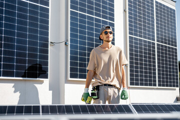 Portrait of handyman standing on a rooftop with installed solar panels on it. Renewable energy for self consumption concept. Idea of installing panels for households