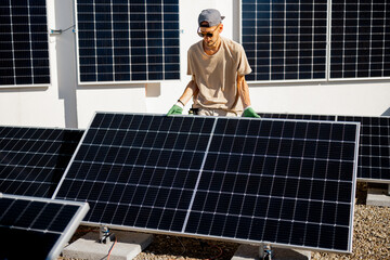 Man installing solar panels on the roof of his house, fitting cell on flat rooftop for self consumption. Renewable energy and sustainability concept