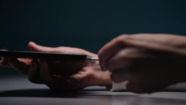 Female hand charging charge mobile phone on black table. Young woman holding smartphone in hand and connecting plug in charger type-c cable. EU law to force USB-C chargers. Shooting in slow motion.