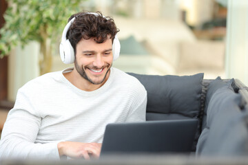 Happy man watching media on laptop in a house terrace