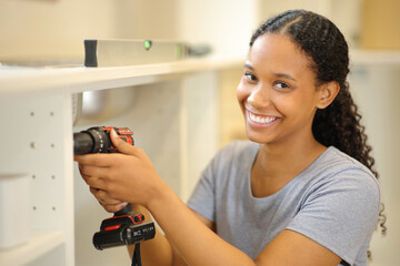 Black woman assembling furniture looking at you