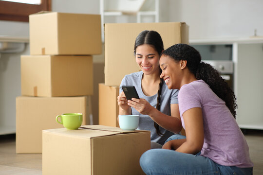 Black and white women checking phone moving house - Powered by Adobe