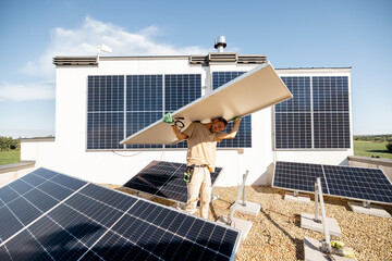 Man carries solar panel on his shoulders while installing solar plant of a rooftop of his property. Renewable energy for self consumption concept. Idea of installing panels for households