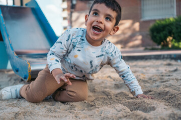 Joyful autistic child playing in sand at playground. Happy young boy with a big smile enjoying...