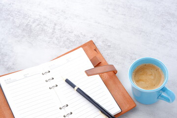 ミルクをたっぷり入れたコーヒー、カフェ・オ・レを飲みながら、システム手帳でデスクワーク中のイメージ
