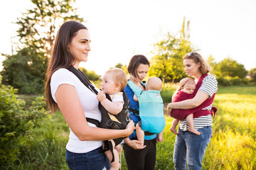 Mothers carrying babies in carriers, slings or wraps. Babywearing.