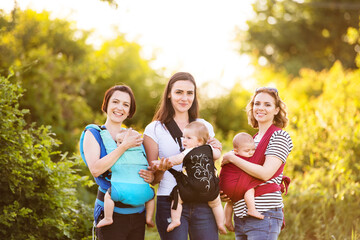Mothers carrying babies in carriers, slings or wraps. Babywearing.