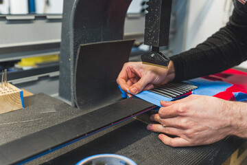 Obraz premium man sticking frets on a guitar calmly by using a machine, guitar manufacture, factory. High quality photo