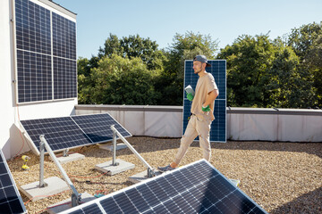 Man looks on solar power station during installation process on a rooftop of his house. Renewable energy for self consumption concept. Idea of installing panels for households