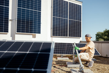Man installs mounts for solar panels on a rooftop of household. Owner of property installing solar...