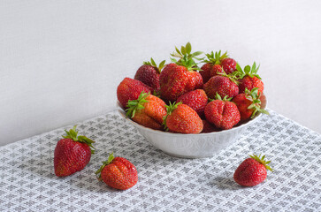 Ripe juicy strawberries in a white plate on the table