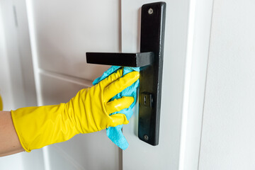 Woman wear gloves with rag cleaning door handle