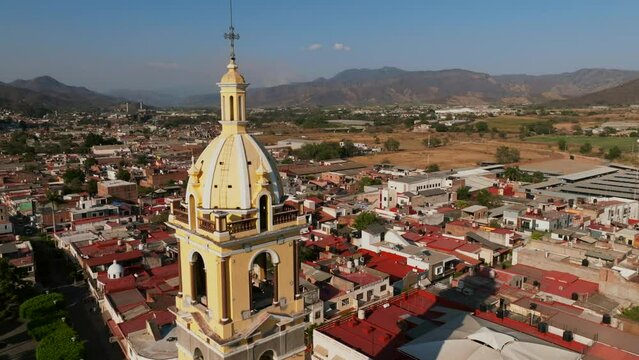 Aerial dolly flight extremely close to the church bell tower in Tamazula de Gordiano city center