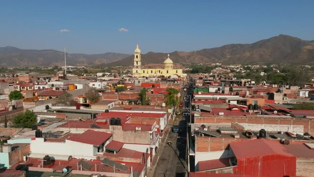 Aerial dolly in flight overlooking a residential area and the Santuario Diosesano in Tamazula de Gordiano