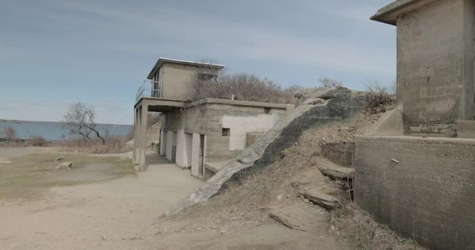 Old war time bunker and ocean lookout on the rocky shores of the Atlantic Ocean in Portland Maine during a overcast day in 4k.
