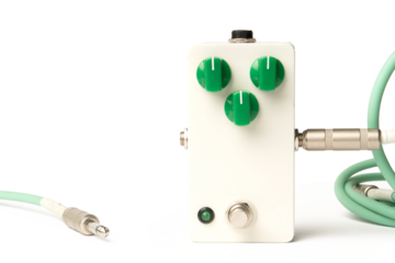 Blank guitar pedal with green knobs and jacks