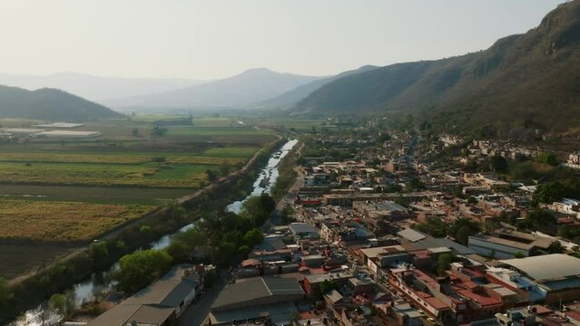Contrasting aerial in Tamazula de Gordiano's housing against crop fields, separated by a river. Aerial dolly in