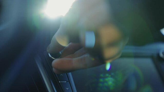 Auto technology concept.close-up of hands turning volume button of car radio.woman driving car.girl turns up volume of the music. acoustics in the car. car audio system. listen to music while driving