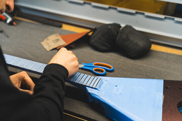 man working on the details of the modern electric guitar at the workshop, guitar making process....