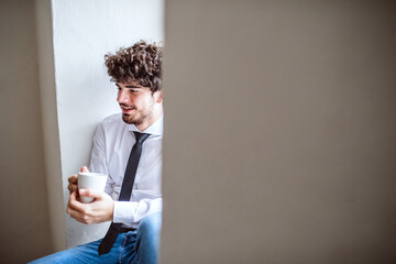 Young man drinking coffee while with colleagues working on a new project in a startup company...