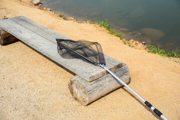 fishing net for fishing on the wooden bench against the backdrop of a pond.summer activities - Powered by Adobe