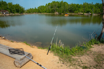 fishing rod and net for fishing against the backdrop of a pond and forest. summer activities