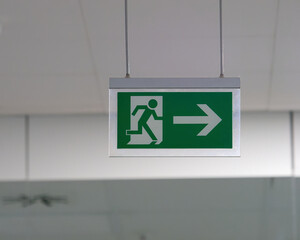 Close-up photo of an escape route (emergency exit) sign on the ceiling of the building