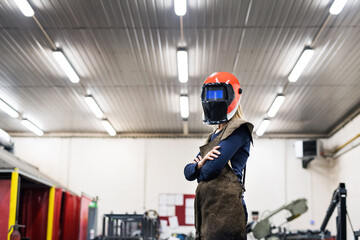 Beautiful blonde woman works as a welder in workshop, operating welding machine, wearing protective...