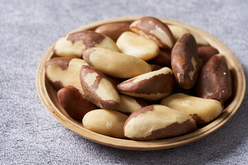close up heap of brazil nut in wood bowl on white table food background