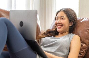 Naklejka premium Young smiling asian woman happy relax use laptop conference work,learning, education, shopping, study online, webinar, online marketing, business, blog, digital internet advertising at home