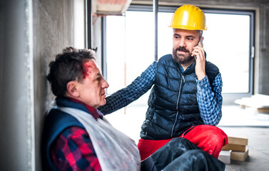 Colleague calling ambulance and giving first aid to injured worker, in pain after accident at...