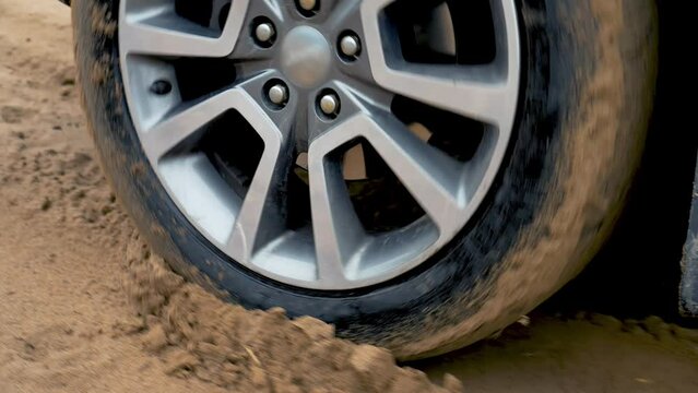 Slide tire of SUV close up. Stuck car wheel. Vehicle in deep wet sand on dirty country terrain. SUV vehicle struggling to gain traction in sand, off road in desert